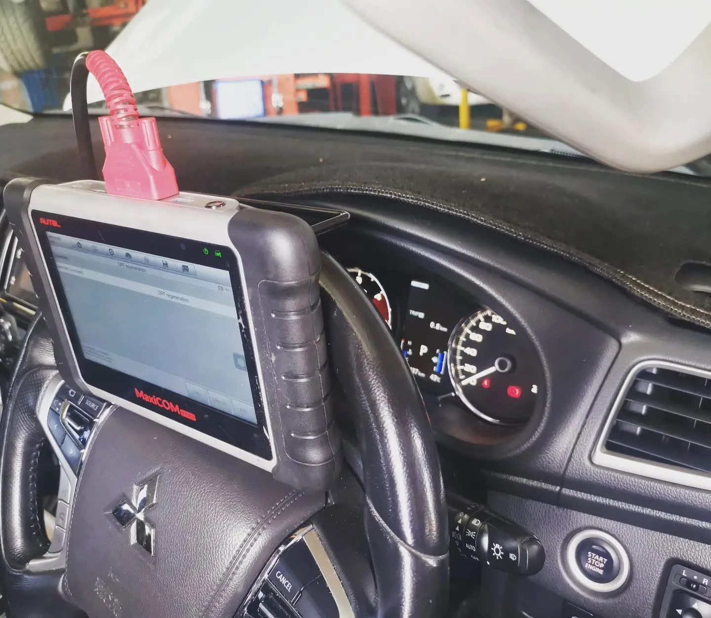 Autel MaxiCOM scan tool plugged into a Mitsubishi during a DPF regeneration in Cairns
