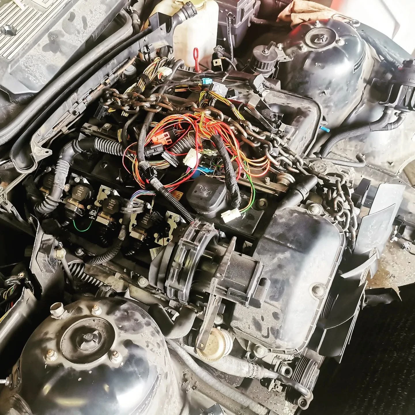 BMW engine bay with wiring loom laid out during an engine repair at S & A Automotive Cairns